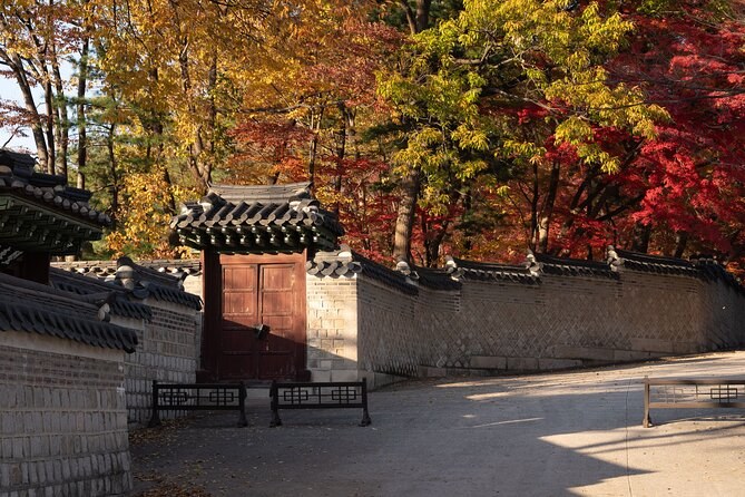 A palace wall and gateway under red autumn maples
